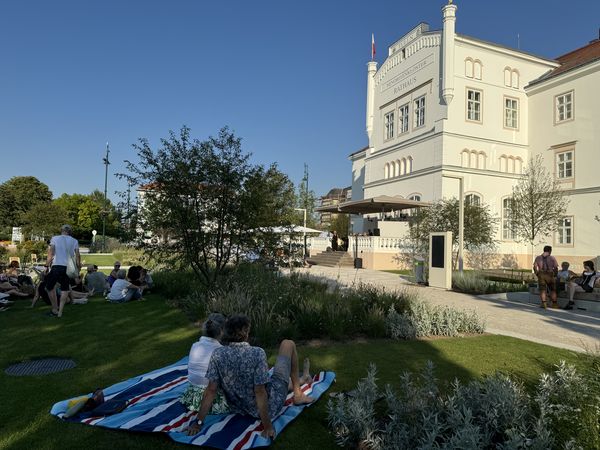 Pärchen siztz auf Picknickdecke am Nibelungenplatz und hört einem Konzert zu 