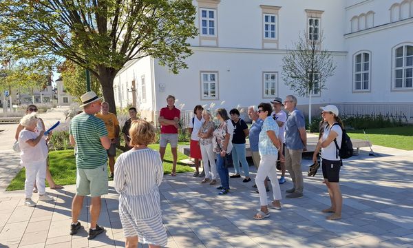 Menschen stehen im Kreis und hören bei einer Führung zu