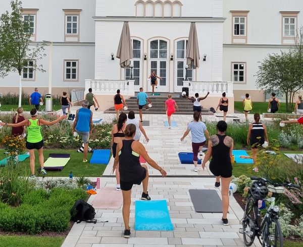 Menschen machen Sport mit Yogamatten vorm Rathaus