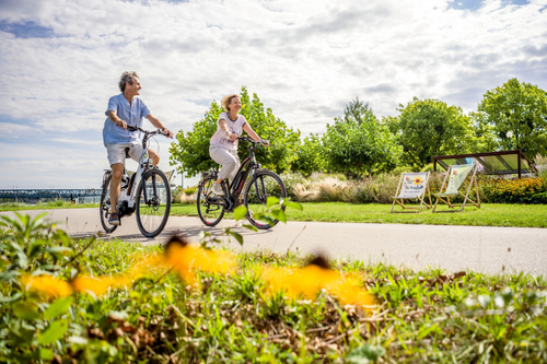 Paar fährt mit E-Bikes an der Donaulände